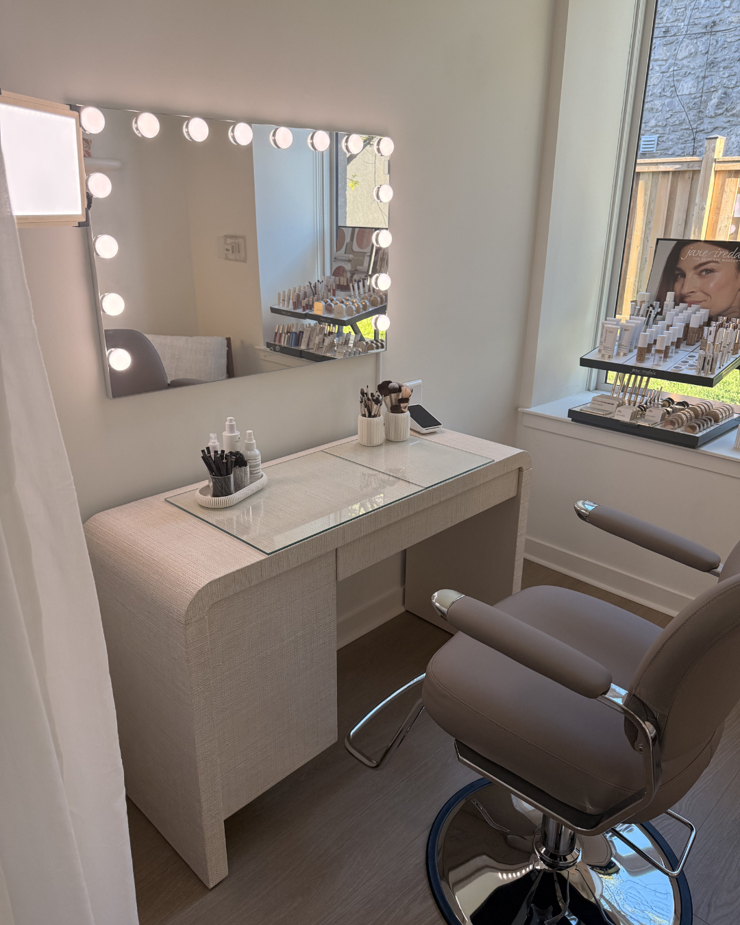 A professional beauty suite with a vanity, mirror and retail display shelf