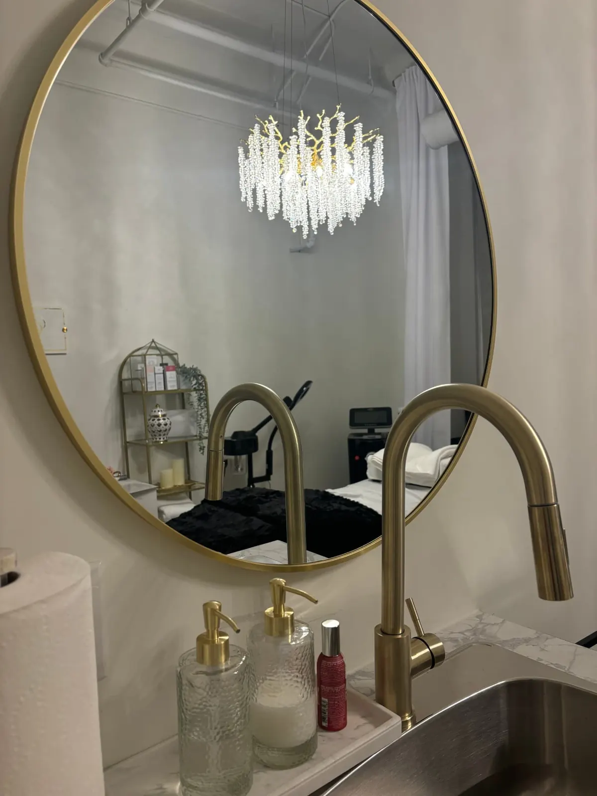 Round gold mirror above the suite's brushed-brass faucet and marble counter