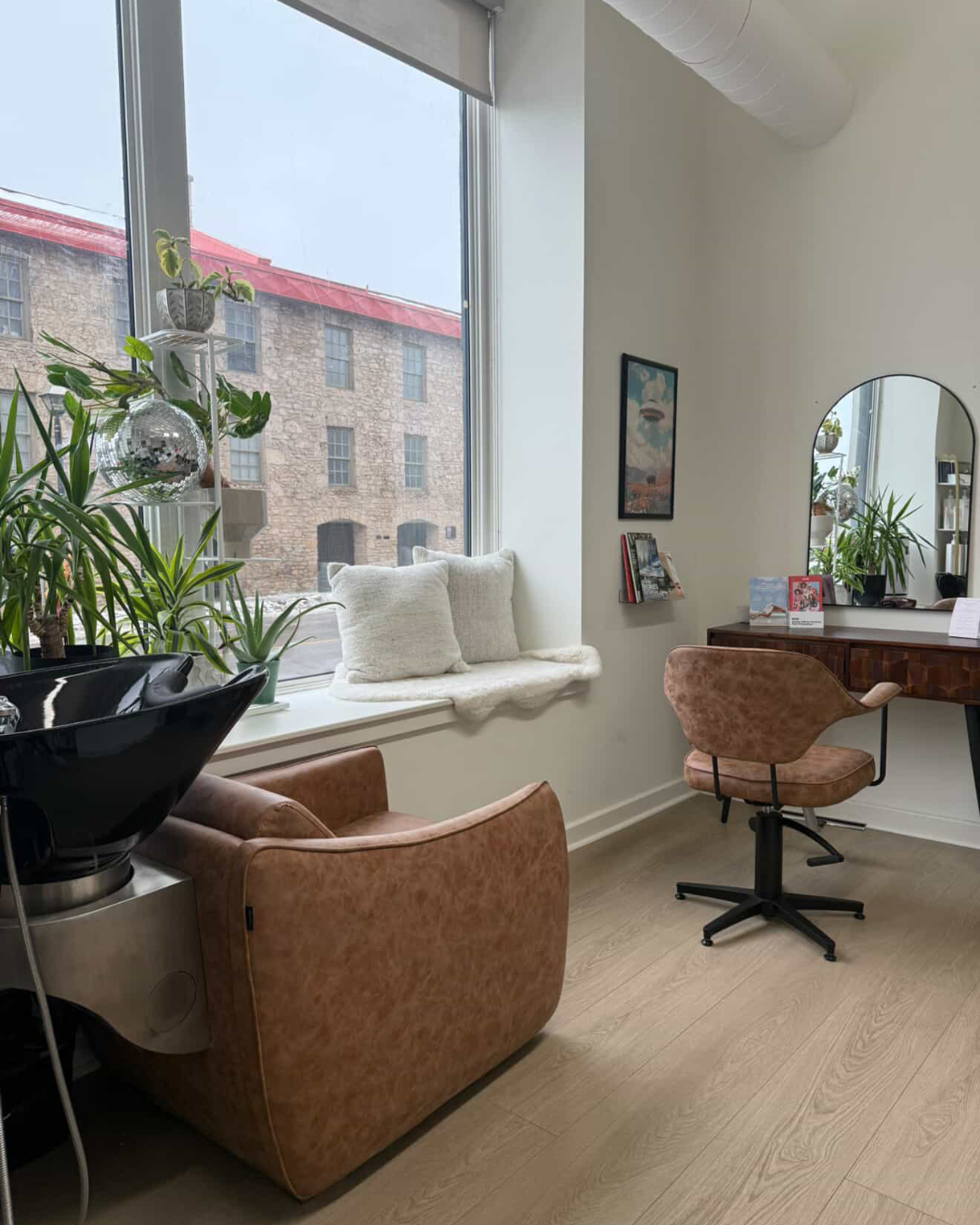 A bright salon suite with a large window, styling chair, mirror and window seat