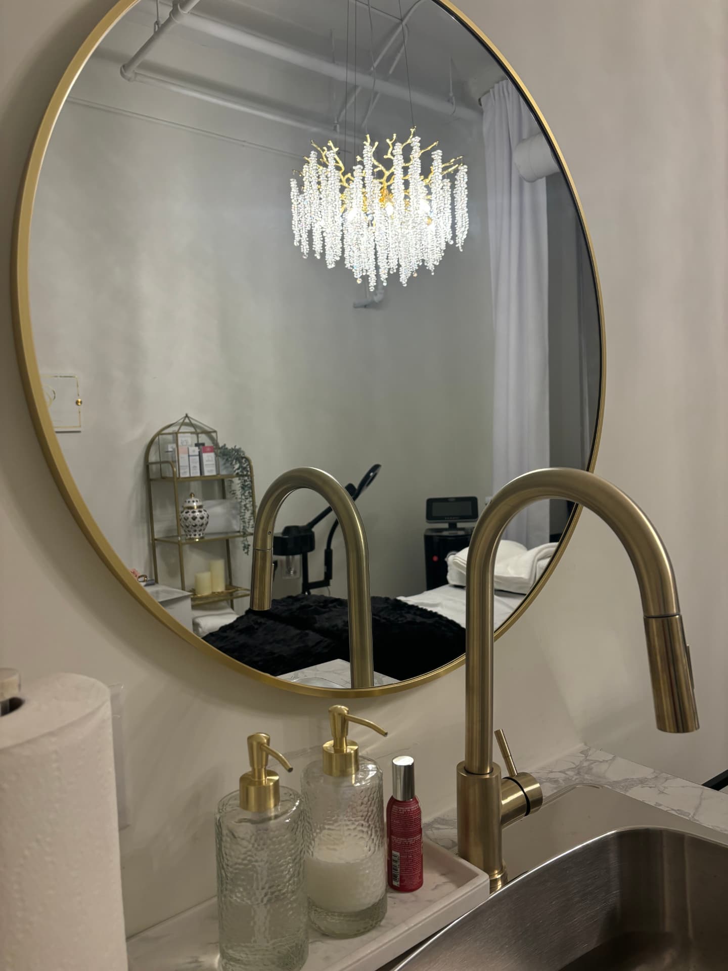 Round gold mirror above the Garden Suite's brushed-brass faucet and marble counter
